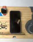 Wooden desk organizer with phone stand, headphones, and other items on a light surface.